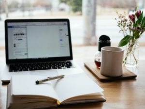 Notebook, computer and coffee for writing great content for website pages
